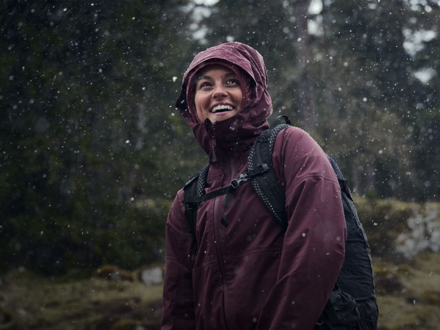 A woman with a rain jacket in the rain in the forest